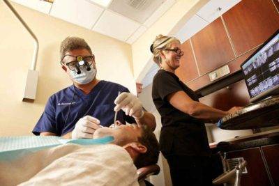 Dr. Henninger examining patient’s mouth at North County Cosmetic and Implant Dentistry in Vista, CA